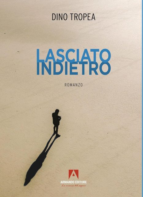 Copertina del romanzo 'Lasciato indietro' di Dino Tropea, con un'immagine che mostra un uomo in silhouette che cammina su una superficie sabbiosa, accompagnato dal titolo del libro in blu e il logo della casa editrice Armando Editore.